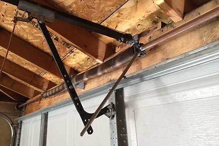 Torsion spring and support brackets mounted above a white garage door in Beacon Hill