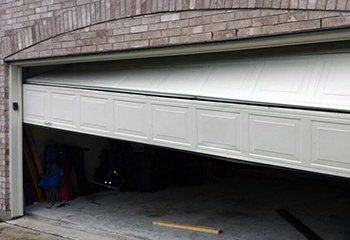 Garage door off tracks with top panel misaligned at a Renton home exterior.