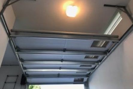 Overhead garage door with light, highlighting opener sensor repair job