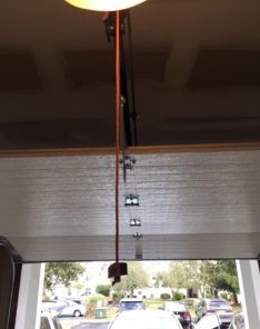 Closeup of a red emergency release cord hanging from a garage door opener in a Puyallup WA residential garage.
