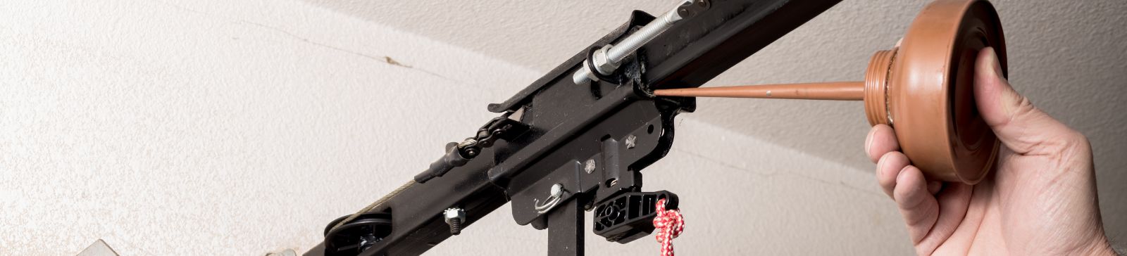 Technician lubricating a garage door opener mechanism, representing expert garage door repair and maintenance services in Bellevue, WA.