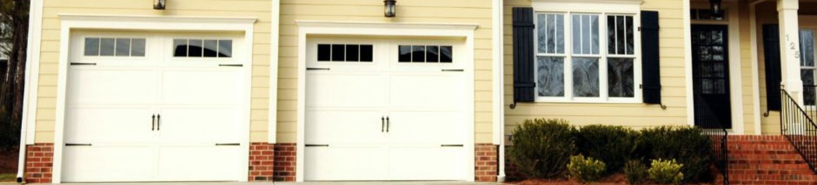 Exterior of suburban Kent home featuring newly installed faux wood Clopay garage doors with modern windows