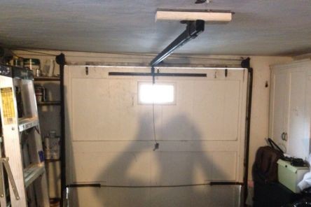 Interior view of a Renton garage with the main door stuck open midway after motor gear failure