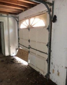 Close-up of top windows on a garage door in Newcastle with break-in damage and dirt, highlighting repair needs