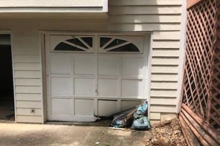Wide view of a Newcastle garage with a visibly damaged garage door panel in need of same day replacement