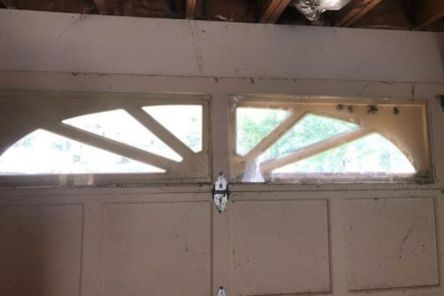 Close-up of top windows on a garage door in Newcastle with break-in damage and dirt, highlighting repair needs