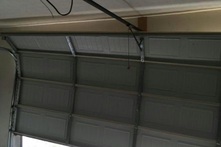 Interior garage photo showing a tilted garage door off track after a spring broke in Tukwila
