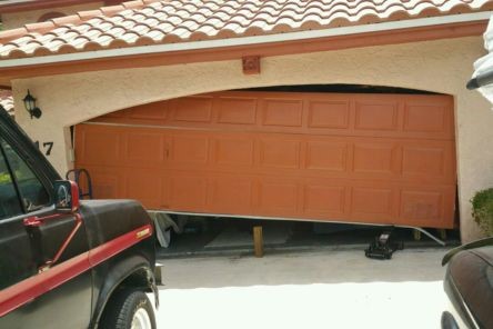 Exterior view of garage door off its tracks and tilted at an angle after spring failure in Tukwila